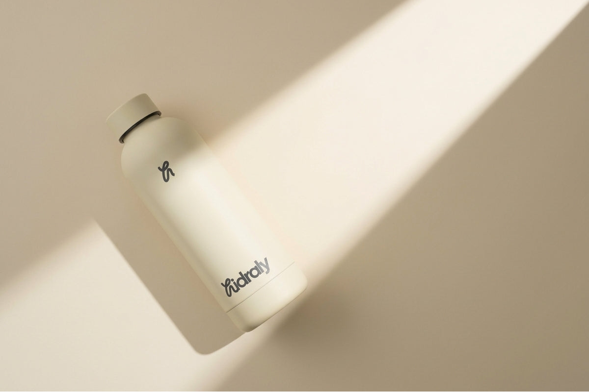 Botella hidraly color crema sobre fondo beige